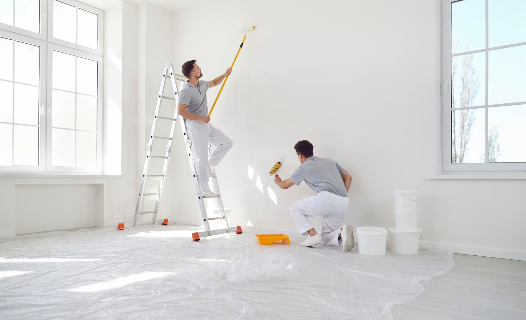 Prestige Home Experts crew painting a fully masked interior room with drop cloths and a step ladder in place