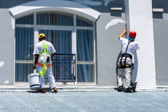 Two Prestige Home Experts crew members working safely on an exterior wall and window surround