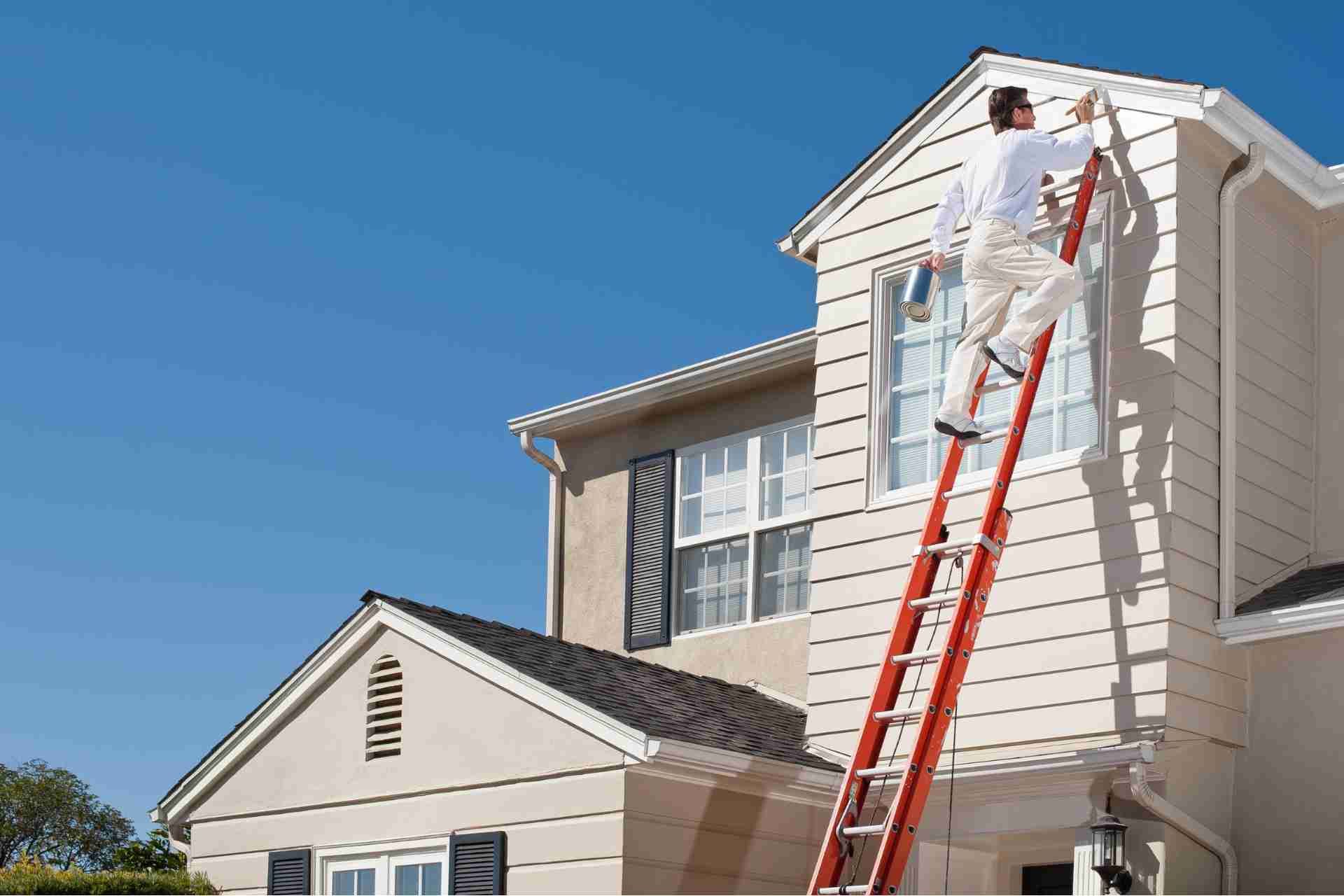 Prestige Home Experts painter on a ladder coating the exterior siding of a Charleston home