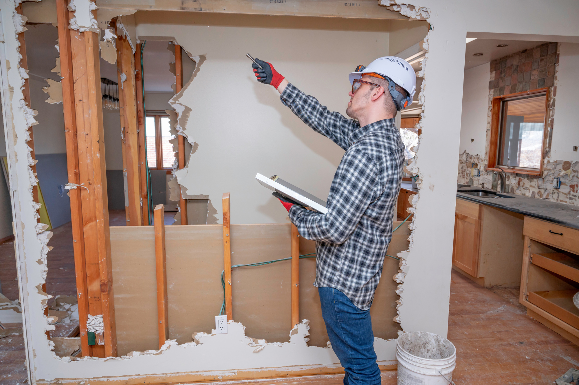 Prestige Home Experts project lead assessing an interior wall and recording notes during a renovation