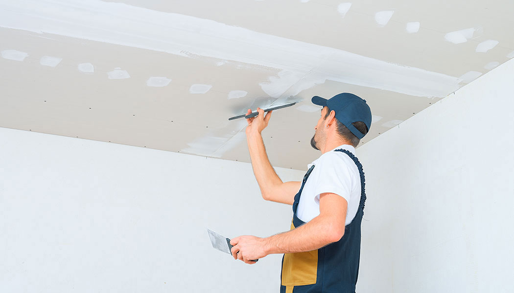 Drywall specialist applying a smoothing compound coat to an interior wall