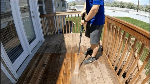 Operator carefully pressure washing the boards of a residential timber deck