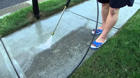 Close view of a rotary surface cleaner stripping algae and grime from paving