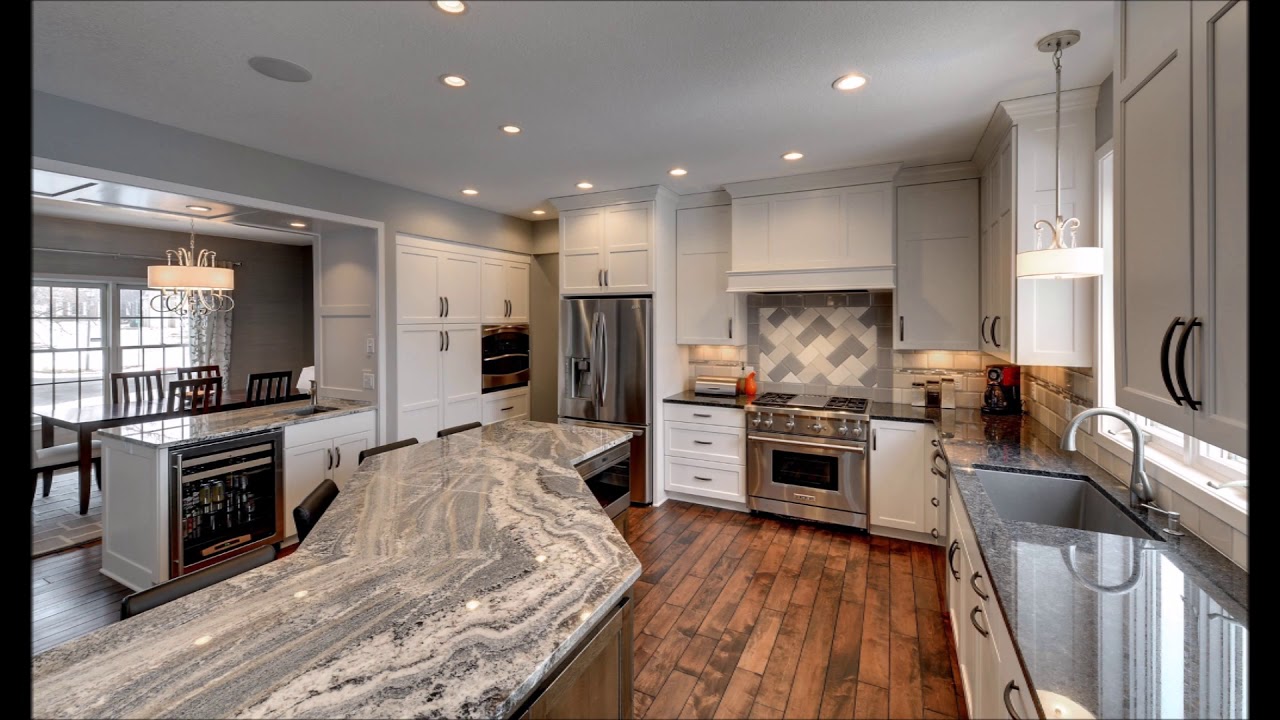 Finished kitchen with a large island, stone worktops and custom white cabinetry