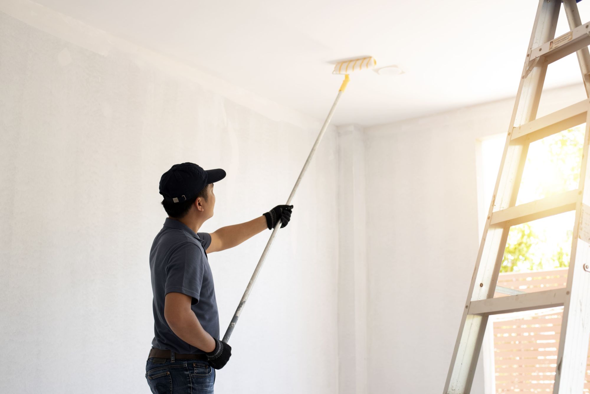 Prestige Home Experts painter rolling a fresh coat onto an interior ceiling with an extension pole