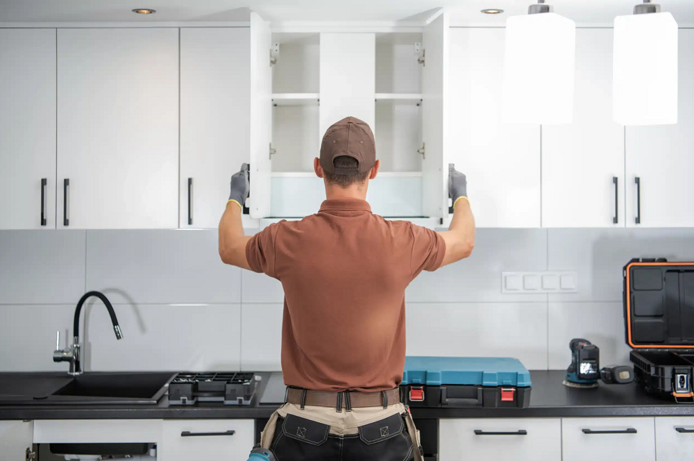 Fitter installing a wall cabinet during a kitchen remodel